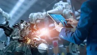 Industrial engineer using a tablet to monitor automated robotic machinery in a factory