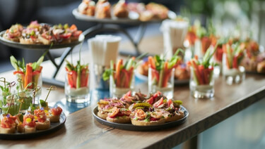 Assorted catered appetizers and vegetable cups displayed on a buffet table
